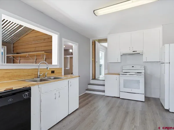 a kitchen with granite countertop a sink cabinets stainless steel appliances and window