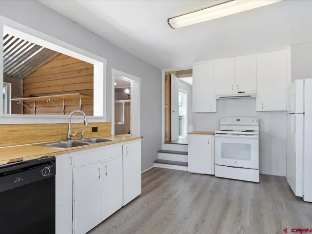 a kitchen with granite countertop a sink cabinets stainless steel appliances and window