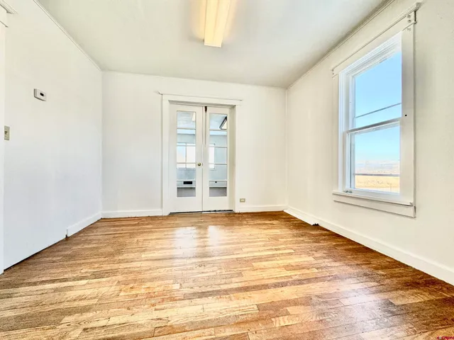 a view of empty room with wooden floor and fan