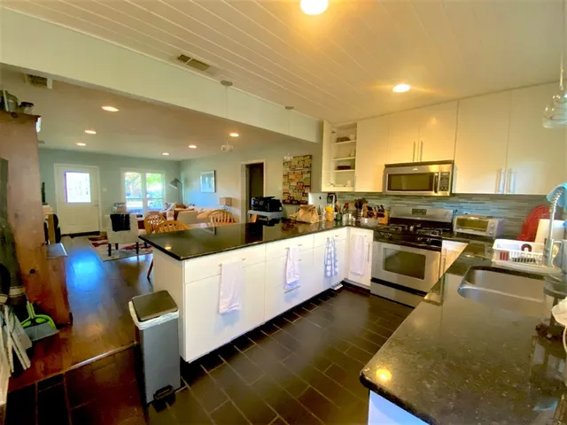 a large white kitchen with lots of counter space furniture and a wooden floor