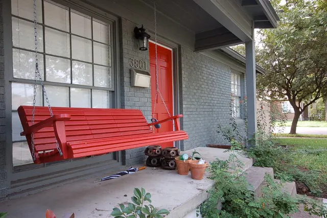 a view of a bench with wooden bench in front of house