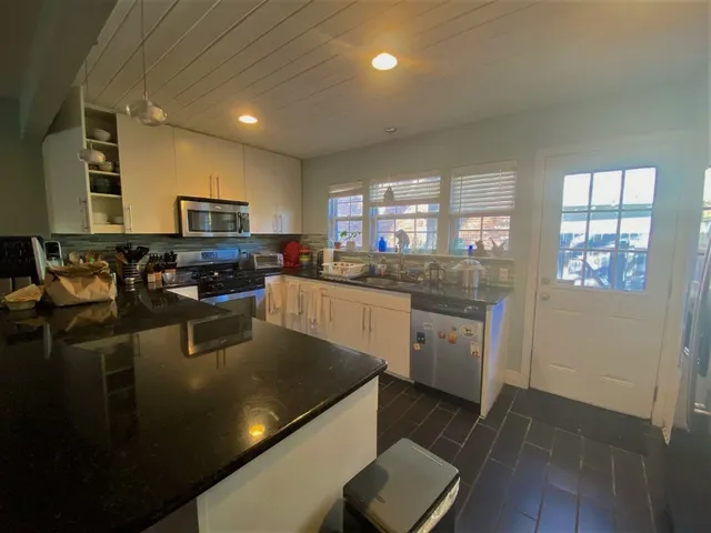 a kitchen with stainless steel appliances granite countertop a sink a stove top oven a counter space and cabinets