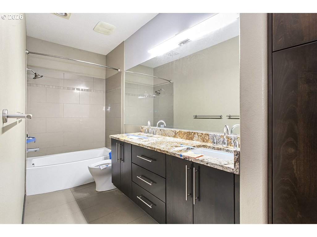 622 South Nevada Street, Unit D Portland, OR 97219 - Photo 34 of 37 a bathroom with a granite countertop sink toilet a large mirror a bathtub and shower
