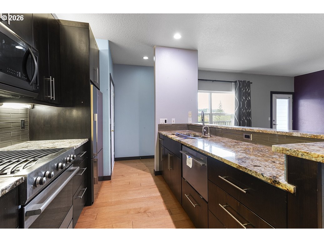 622 South Nevada Street, Unit D Portland, OR 97219 - Photo 10 of 37 a kitchen with stainless steel appliances granite countertop a stove a sink and a refrigerator