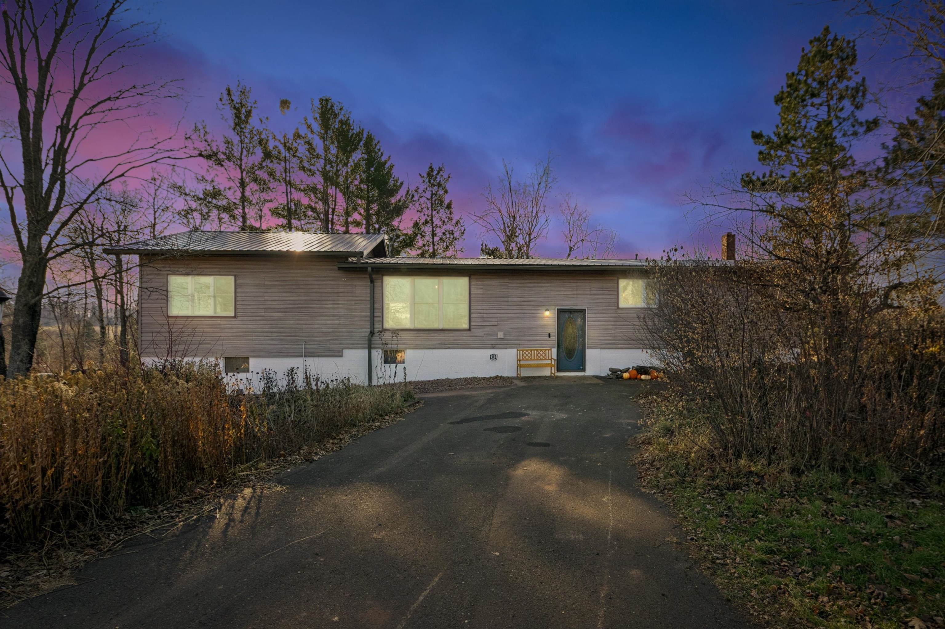 Back of house with driveway and a metal roof