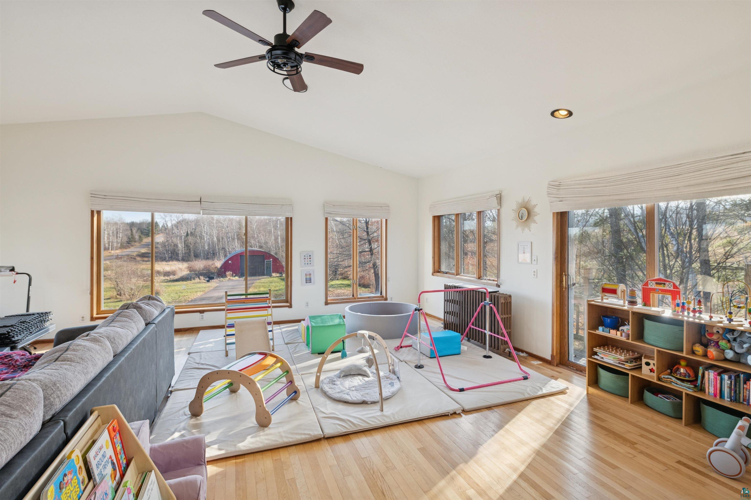 19805 Keystone Road Mason, WI 54856 - Photo 12 of 25 Recreation room with plenty of natural light, wood finished floors, a ceiling fan, vaulted ceiling, and radiator heating unit