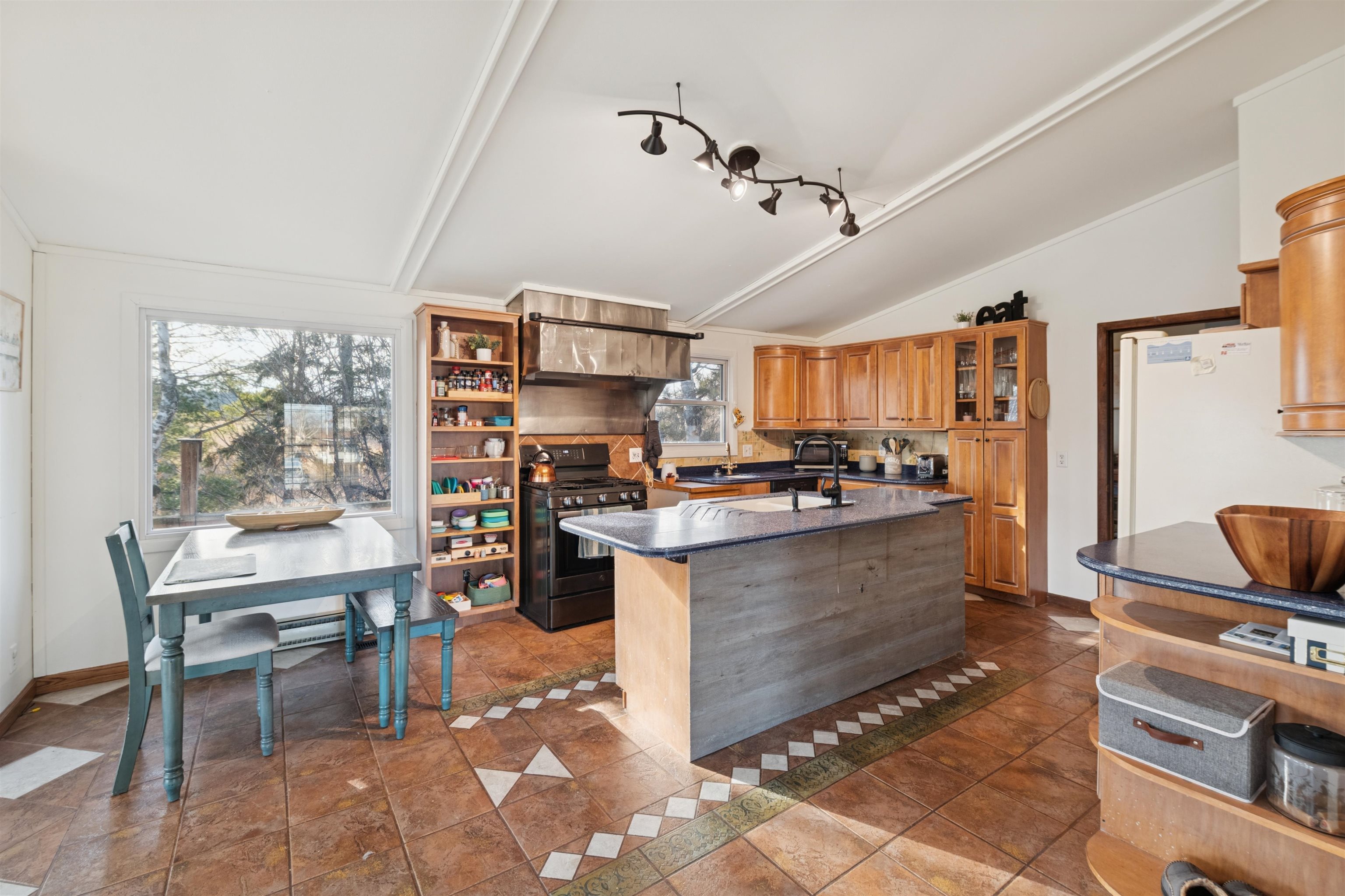 19805 Keystone Road Mason, WI 54856 - Photo 5 of 25 Kitchen featuring open shelves, gas stove, a kitchen island with sink, brown cabinetry, and glass insert cabinets