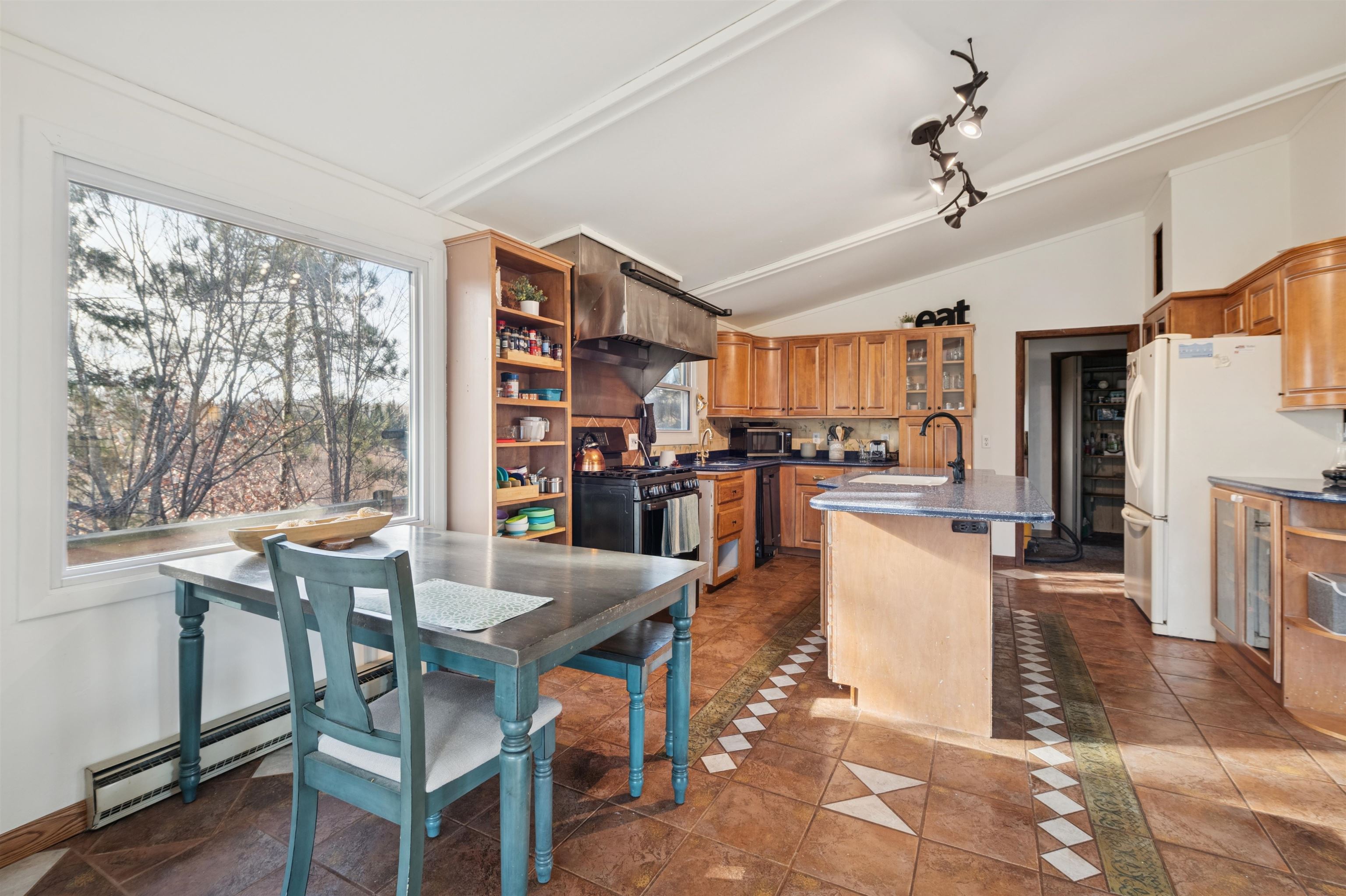 19805 Keystone Road Mason, WI 54856 - Photo 6 of 25 Kitchen featuring vaulted ceiling, healthy amount of natural light, glass insert cabinets, a baseboard radiator, and freestanding refrigerator