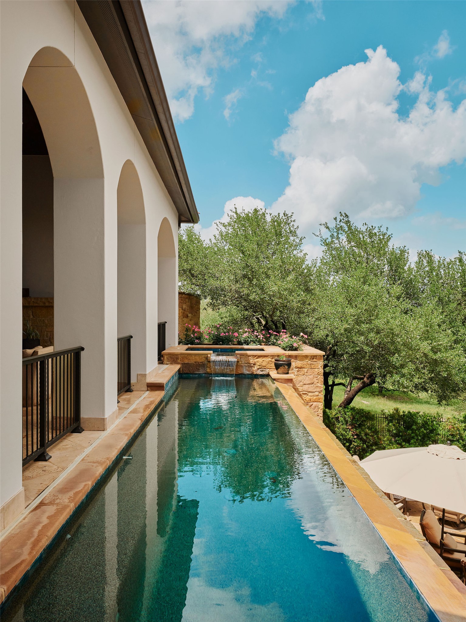 433 Brandon Way Austin, TX 78733 - Photo 25 of 40 An inviting infinity pool extends from an elegant arched patio, offering tranquil water views.
