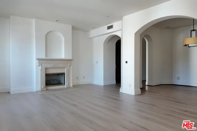 an empty room with wooden floor and a fireplace