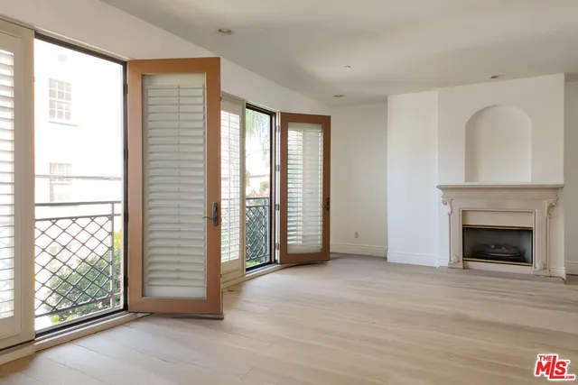 an empty room with windows and fireplace