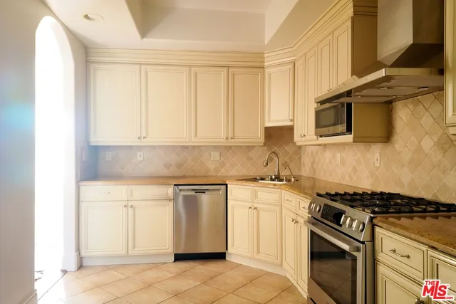 a kitchen with granite countertop a sink stove and white cabinets
