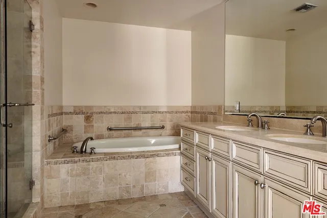 a bathroom with a double vanity sink a mirror and a bathtub