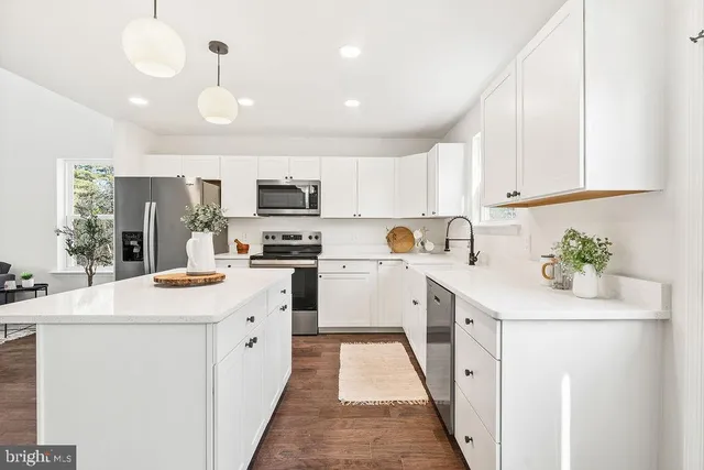 a kitchen with white cabinets and window