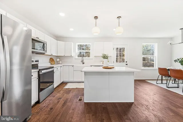 a kitchen with kitchen island granite countertop a sink cabinets and stainless steel appliances