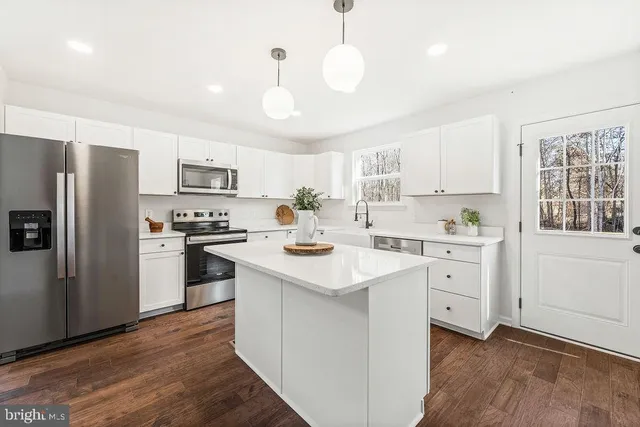 a kitchen with a sink dishwasher a refrigerator a stove and white cabinets with wooden floor