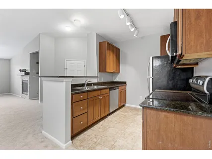 a kitchen with granite countertop a sink a stove and cabinets
