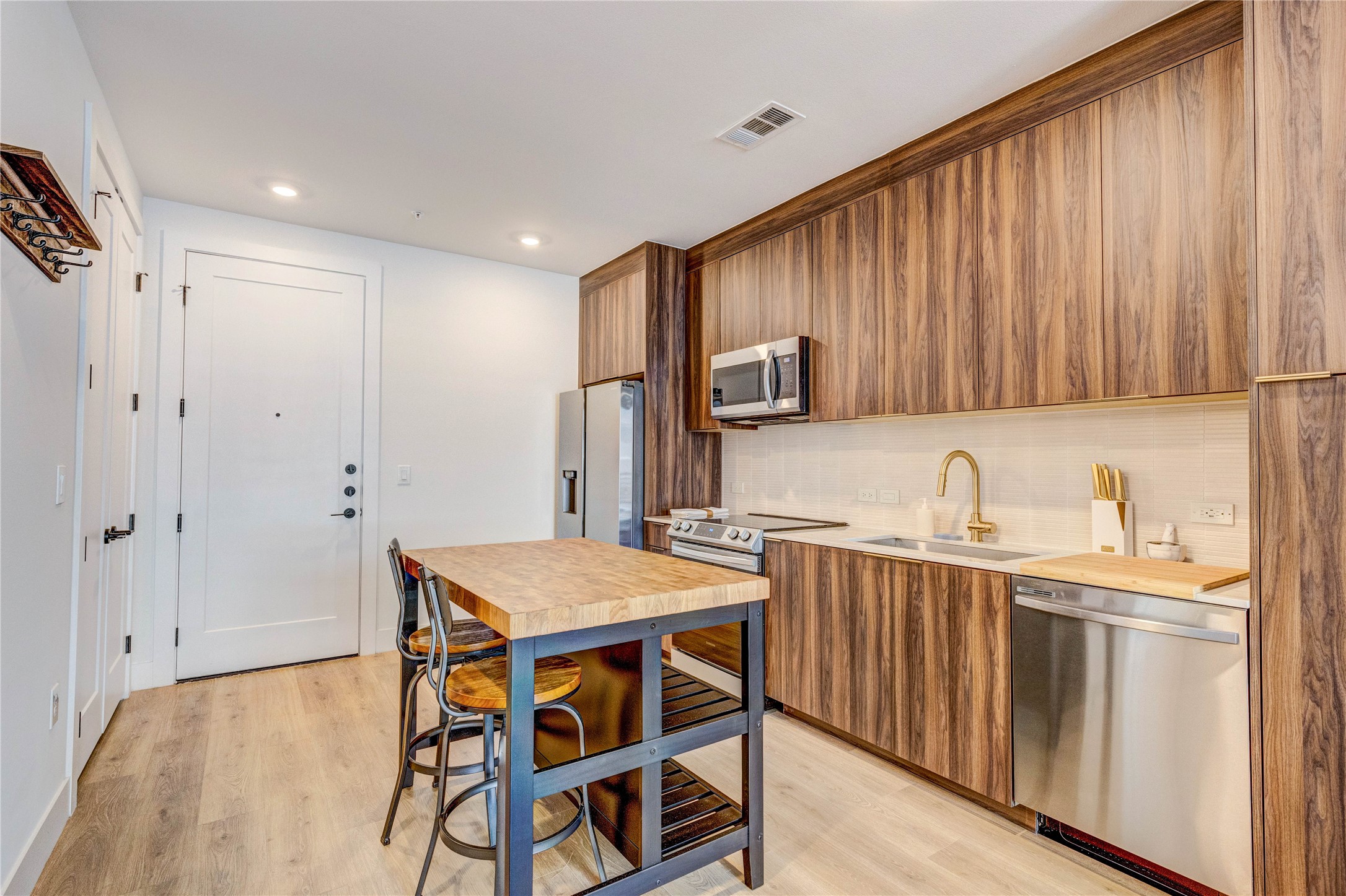 1701 Simond Avenue, Unit 301 Austin, TX 78723 - Photo 11 of 26 a kitchen with stainless steel appliances kitchen island granite countertop a table chairs sink and cabinets