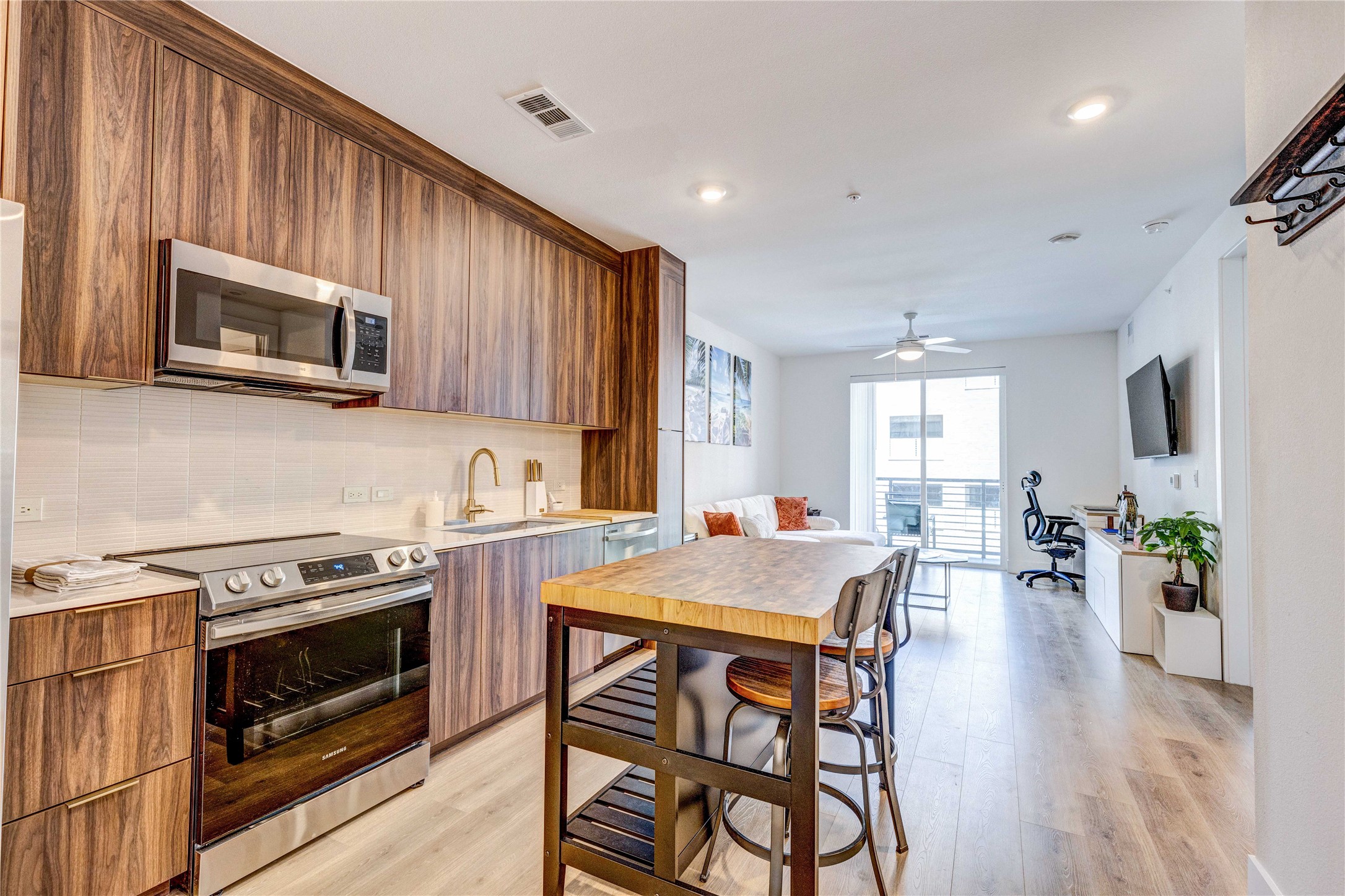 1701 Simond Avenue, Unit 301 Austin, TX 78723 - Photo 12 of 26 a kitchen with a stove top oven a sink dishwasher a dining table and chairs with wooden floor