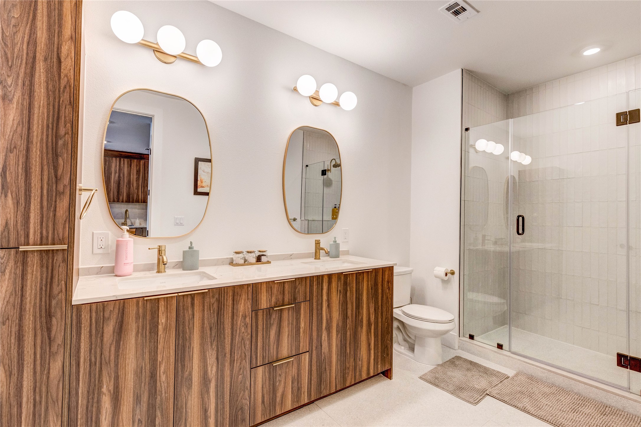 1701 Simond Avenue, Unit 301 Austin, TX 78723 - Photo 8 of 26 a bathroom with double vanity sinks a toilet a mirror and shower