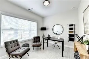 a work room with furniture a rug potted plant and a large window