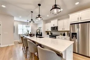 a kitchen with stainless steel appliances a dining table chairs refrigerator and microwave
