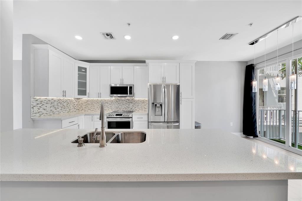 2725 Northeast 8th Avenue, Unit 113 Wilton Manors, FL 33334 - Photo 20 of 72 a large kitchen with stainless steel appliances a large counter top a stove and a refrigerator