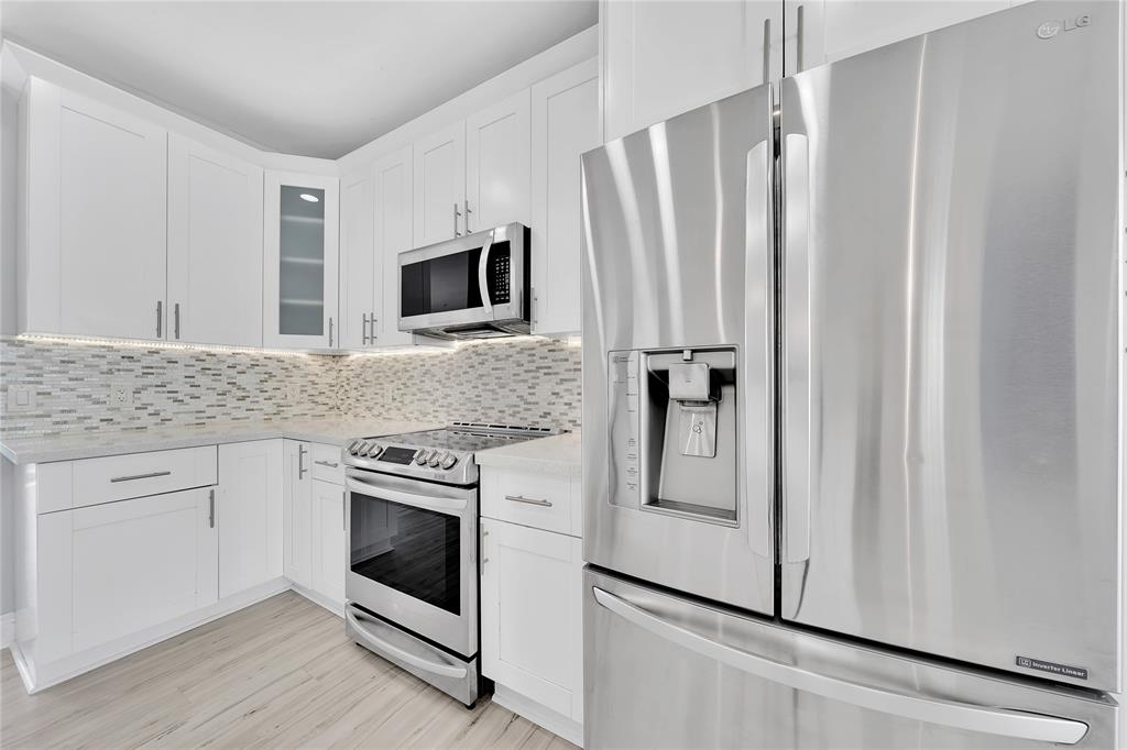 2725 Northeast 8th Avenue, Unit 113 Wilton Manors, FL 33334 - Photo 22 of 72 a kitchen with granite countertop white cabinets and white appliances