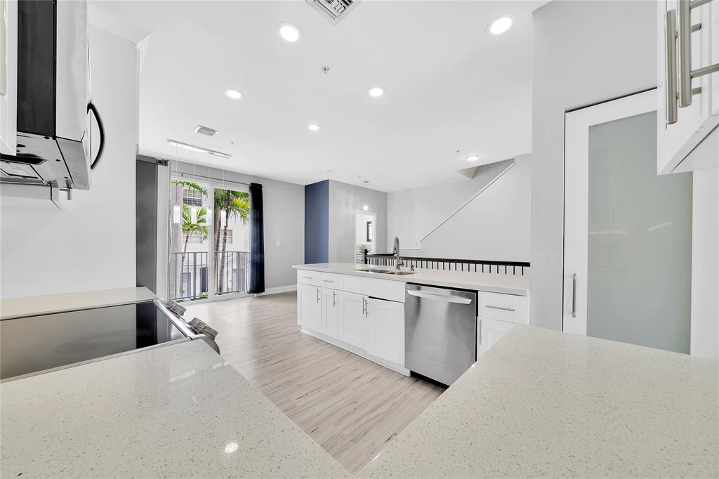 2725 Northeast 8th Avenue, Unit 113 Wilton Manors, FL 33334 - Photo 23 of 72 a large white kitchen with a refrigerator a sink dishwasher a stove and a dining table with wooden floor