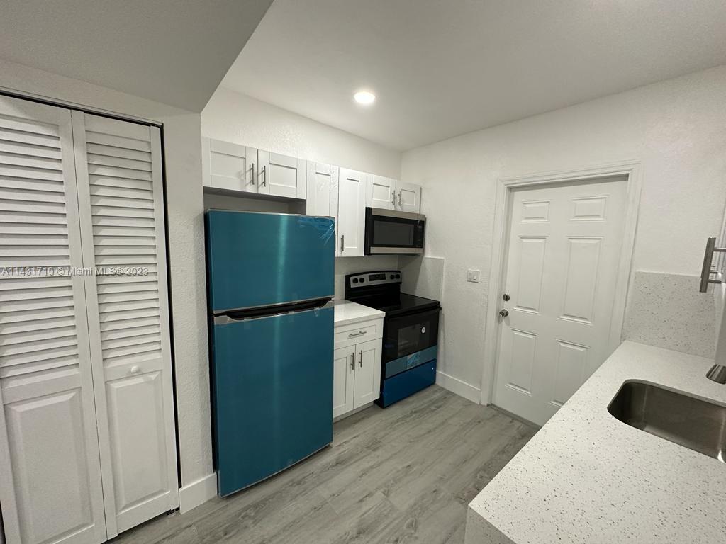 429 Southwest 7th Avenue Homestead, FL 33030 - Photo 6 of 16 a kitchen with a refrigerator a stove top oven and wooden floor
