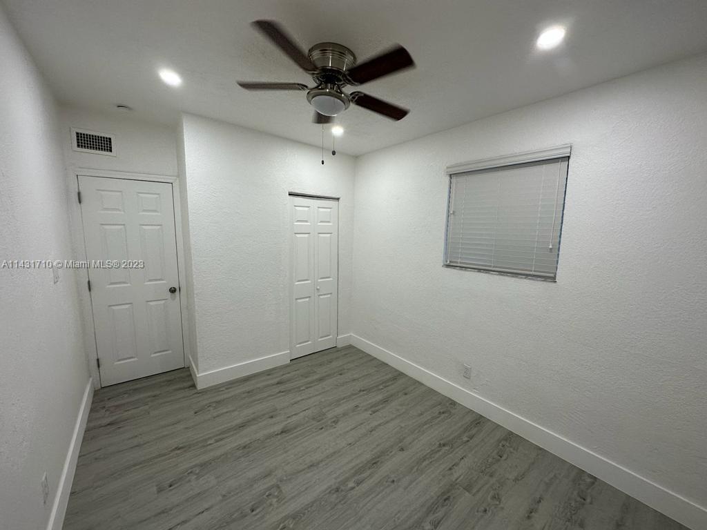 429 Southwest 7th Avenue Homestead, FL 33030 - Photo 10 of 16 an empty room with wooden floor and a ceiling fan