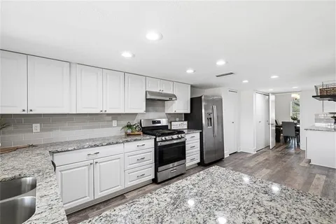 a kitchen with granite countertop a sink a counter top space stainless steel appliances and cabinets