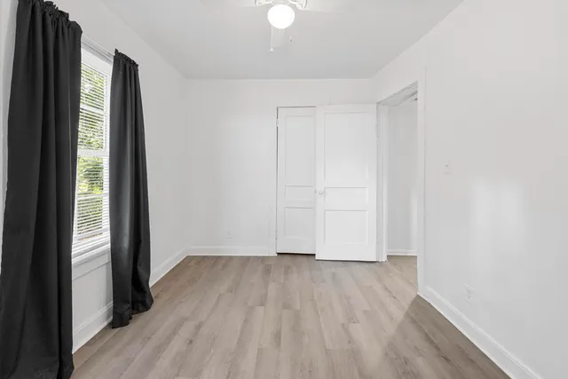a view of an empty room with wooden floor and a window