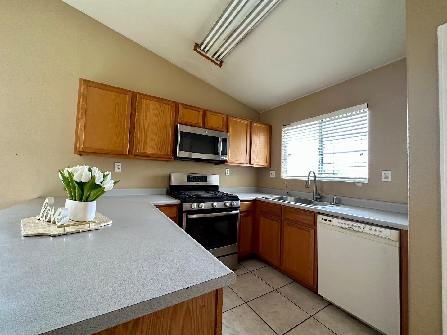 1060 Viewpointe Street Soledad, CA 93960 - Photo 3 of 11 a kitchen with stainless steel appliances granite countertop a sink dishwasher stove top oven and microwave with wooden floor