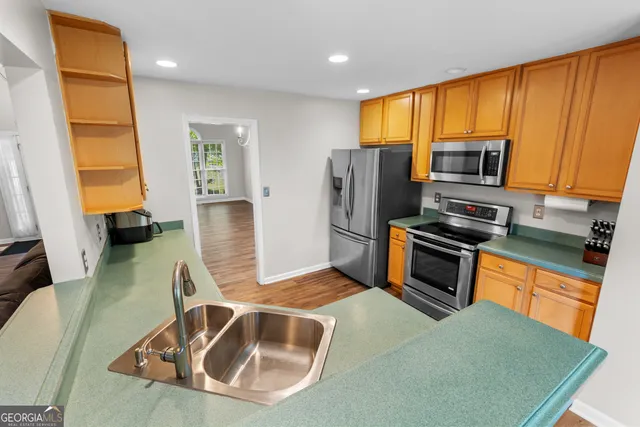 a kitchen with stainless steel appliances a stove a refrigerator a sink a stove top oven with wooden floor