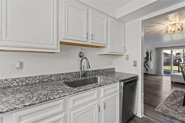 a kitchen with granite countertop white cabinets and a sink
