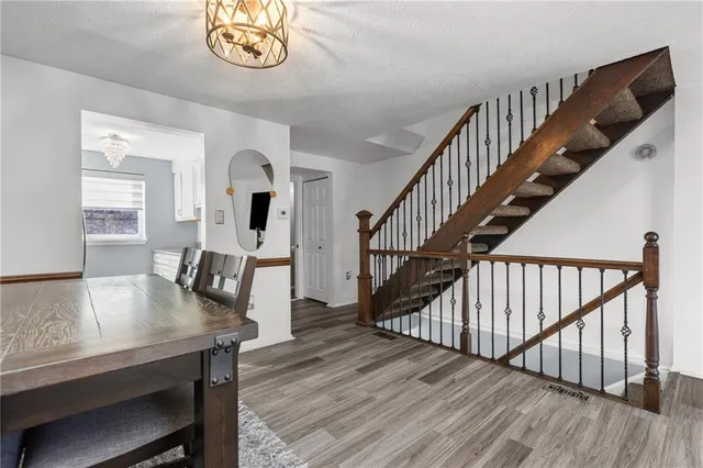 a dining room with wooden floor a chandelier a wooden table and chairs