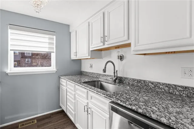 a kitchen with stainless steel appliances granite countertop white cabinets and a sink