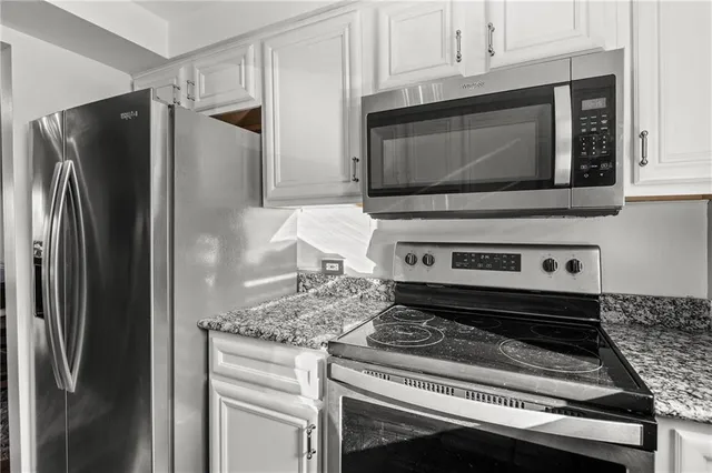 a kitchen with granite countertop a stove microwave and refrigerator