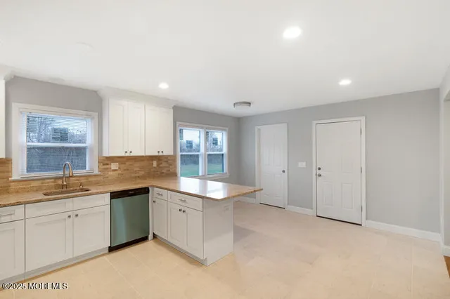 a large white kitchen with a sink and dishwasher with white cabinets