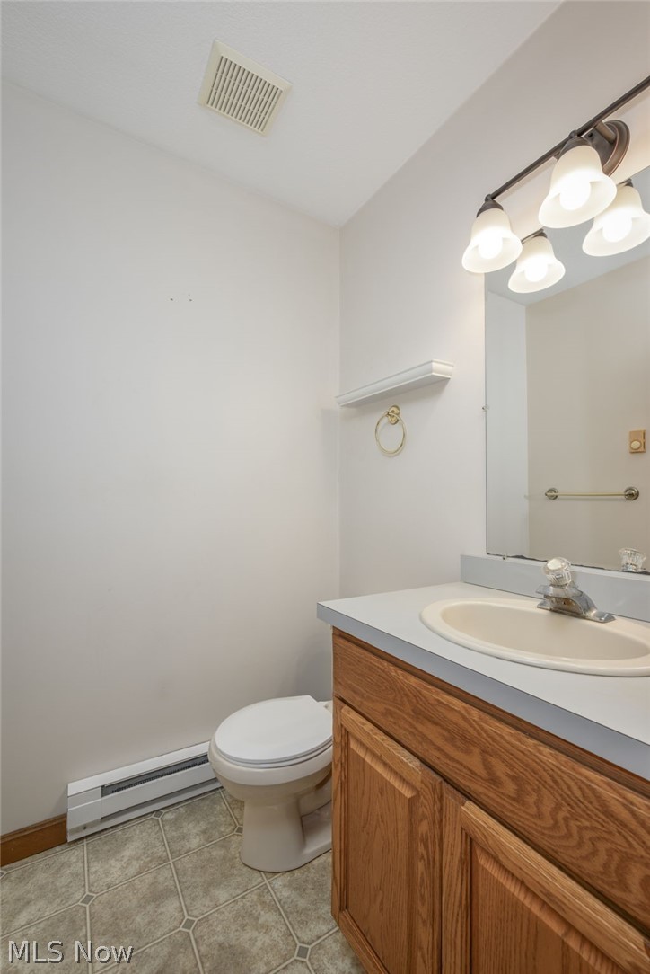 8464-8446 Tallmadge Road Diamond, OH 44412 - Photo 14 of 39 Half bathroom with baseboard heating, vanity, and light tile patterned flooring