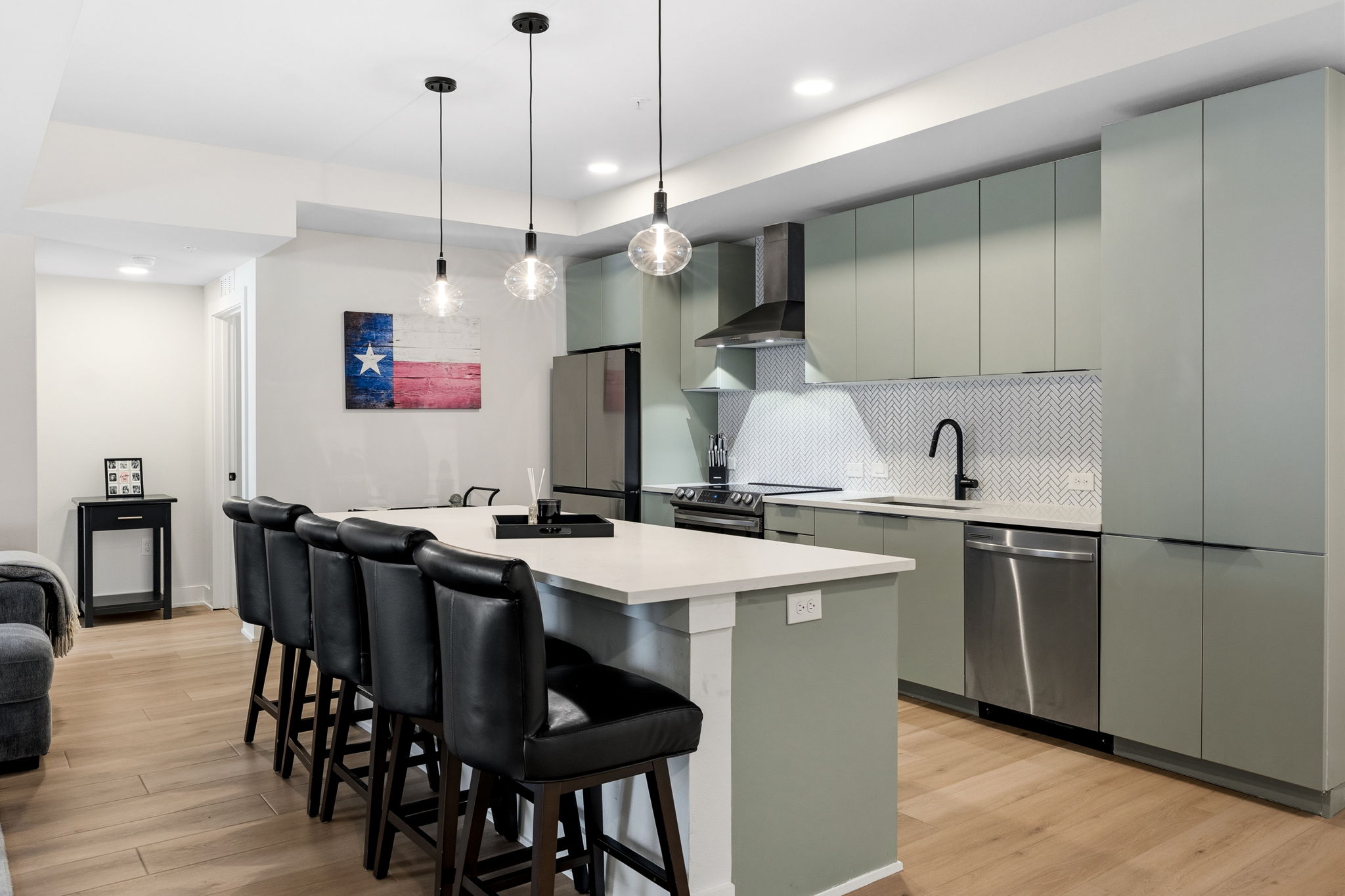 2500 Longview Street, Unit 116 Austin, TX 78705 - Photo 2 of 27 Open-concept kitchen and living area featuring light wood-finish flooring, a kitchen island with integrated microwave, pendant lighting, and recessed lights
