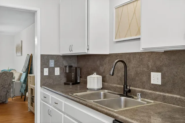 a kitchen with stainless steel appliances granite countertop a stove top oven a refrigerator a sink and dishwasher with wooden floor