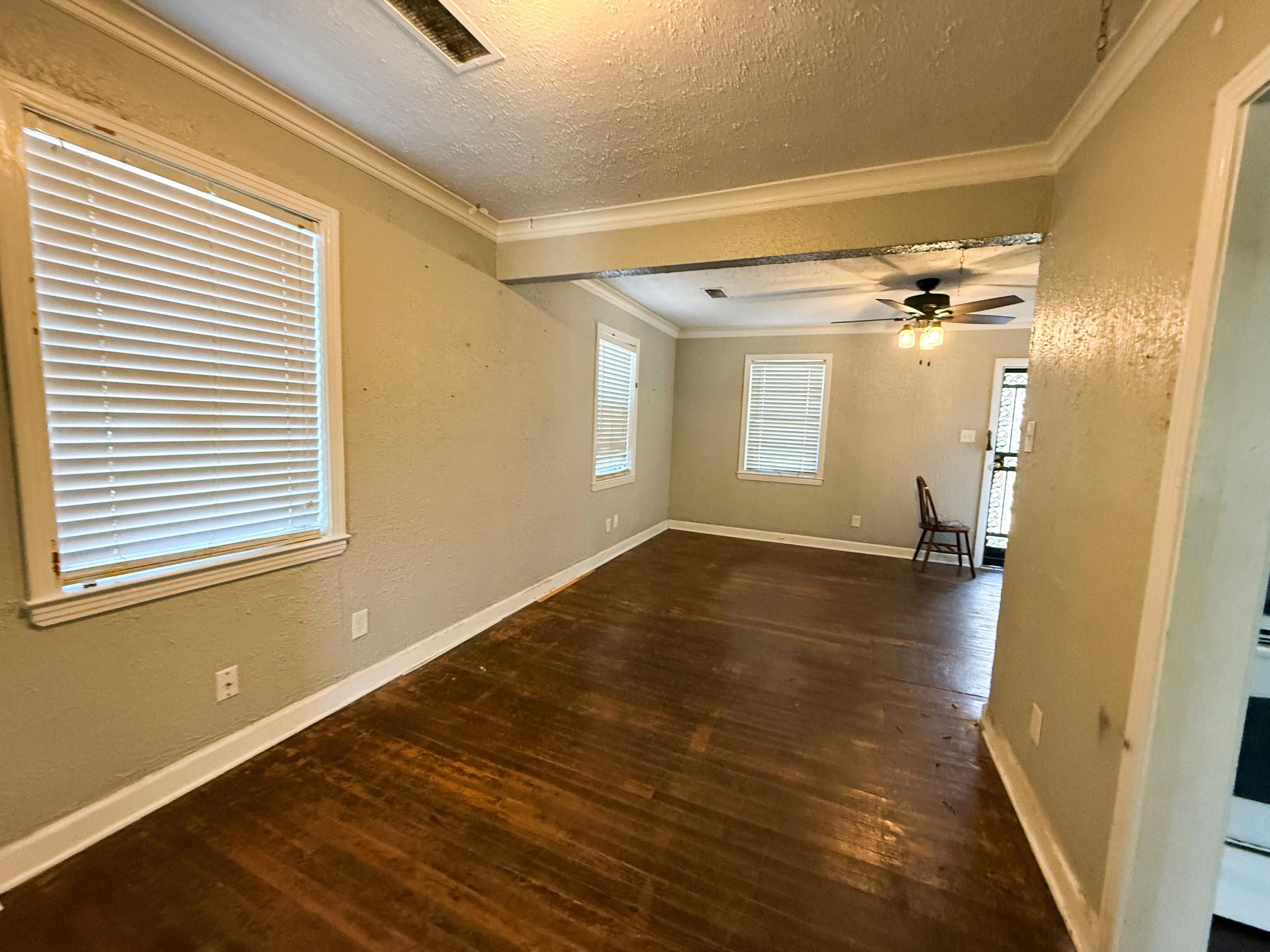 1027 Waring Road Memphis, TN 38122 - Photo 10 of 14 Empty room with dark wood finished floors, a textured wall, a textured ceiling, ornamental molding, and ceiling fan