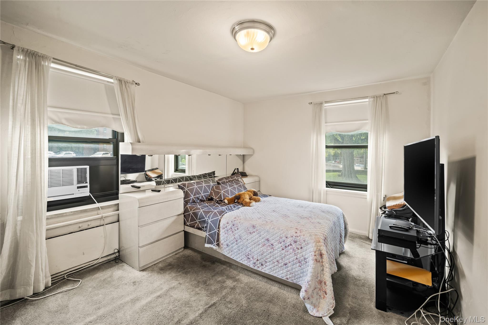 211-02 75th Avenue, Unit 1L Queens, NY 11364 - Photo 8 of 16 a bedroom with a bed and a flat screen tv