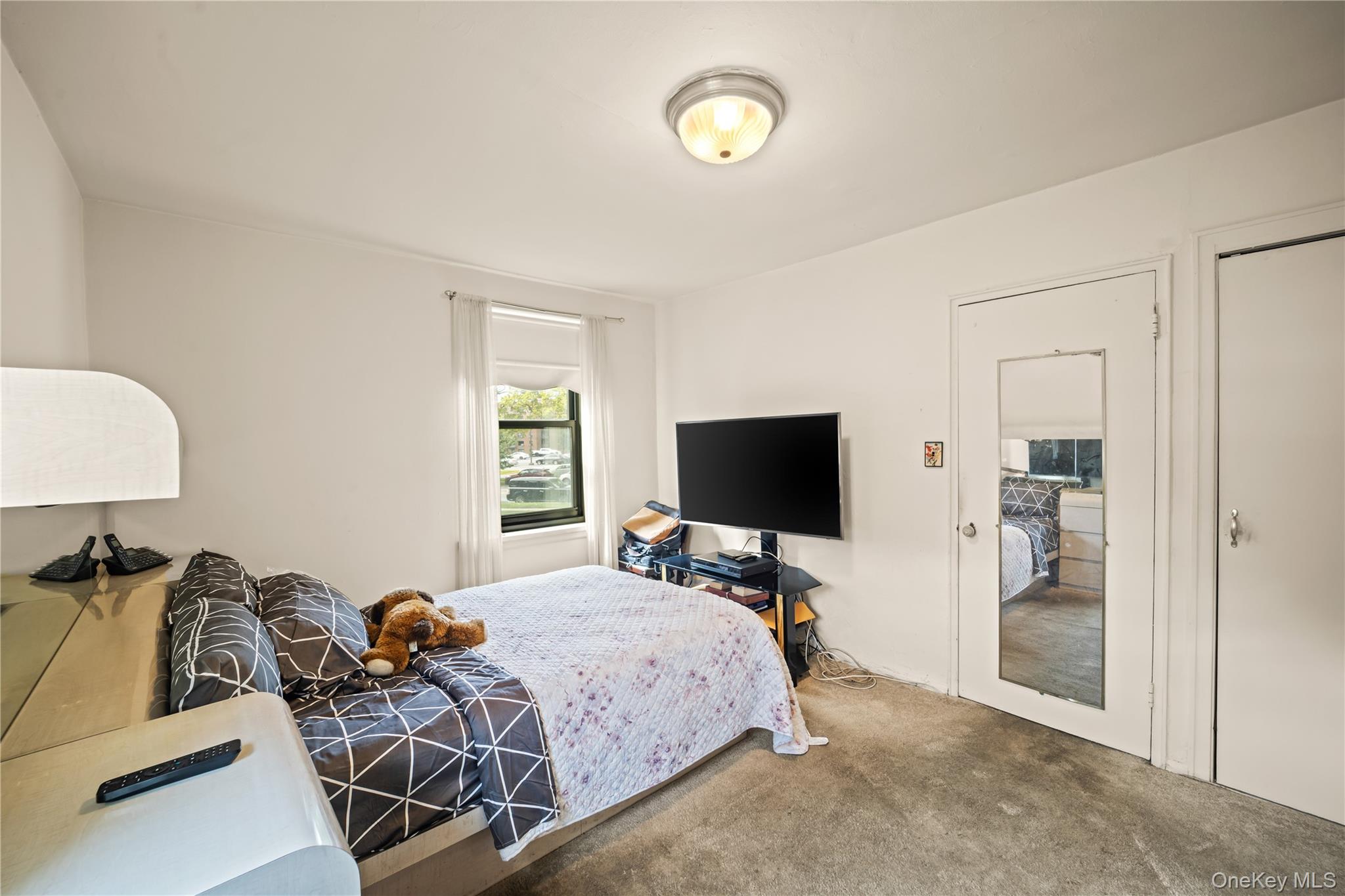 211-02 75th Avenue, Unit 1L Queens, NY 11364 - Photo 9 of 16 a bedroom with furniture and a flat screen tv