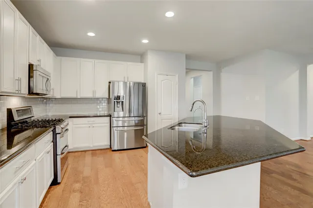 a kitchen with stainless steel appliances granite countertop a sink a stove and a refrigerator