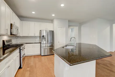 a kitchen with stainless steel appliances granite countertop a sink a stove and a refrigerator