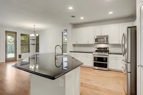 a kitchen with stainless steel appliances granite countertop a sink refrigerator and cabinets