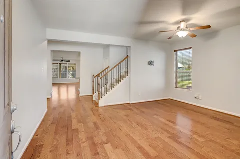 a view of an empty room with wooden floor and a chandelier fan